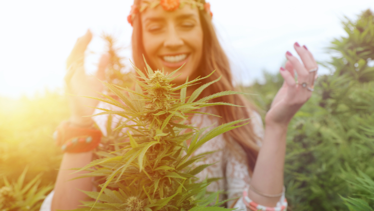 A woman stands behind a legal cannabis plant being cultivated outdoors